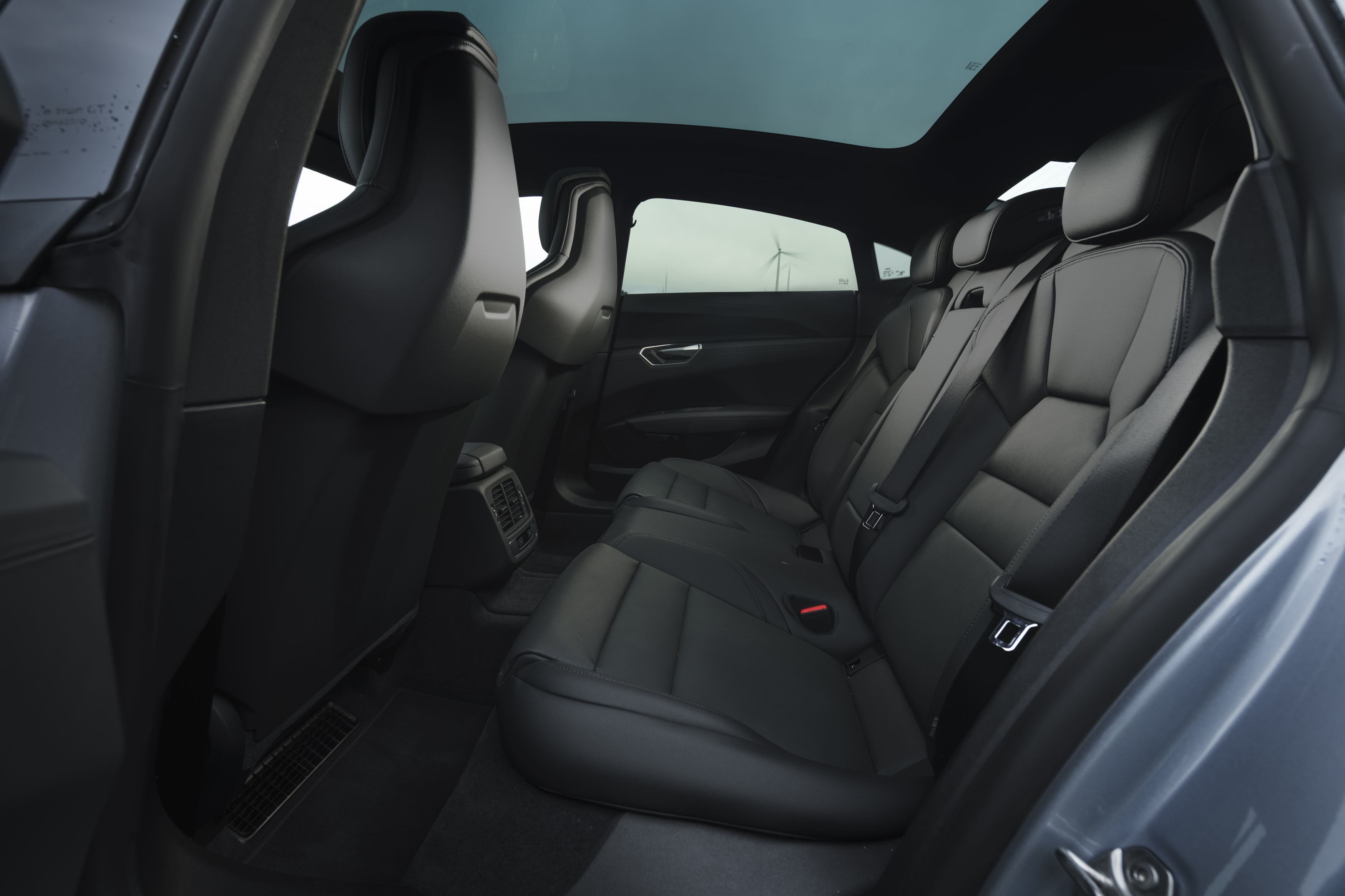 Spacious car interior with black leather rear seats and a panoramic glass roof.