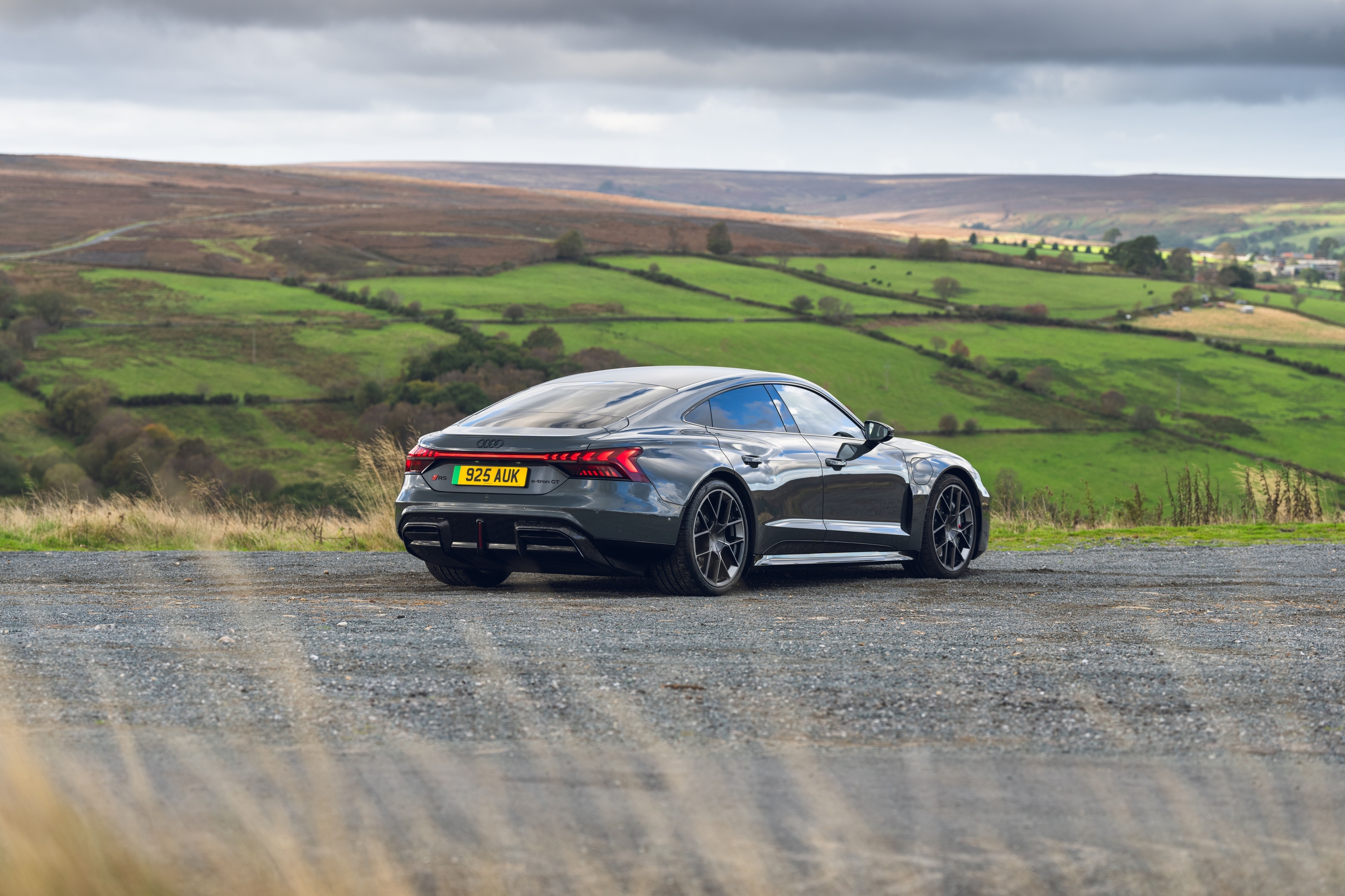 Grey Audi electric car overlooking green fields and open moorland.
