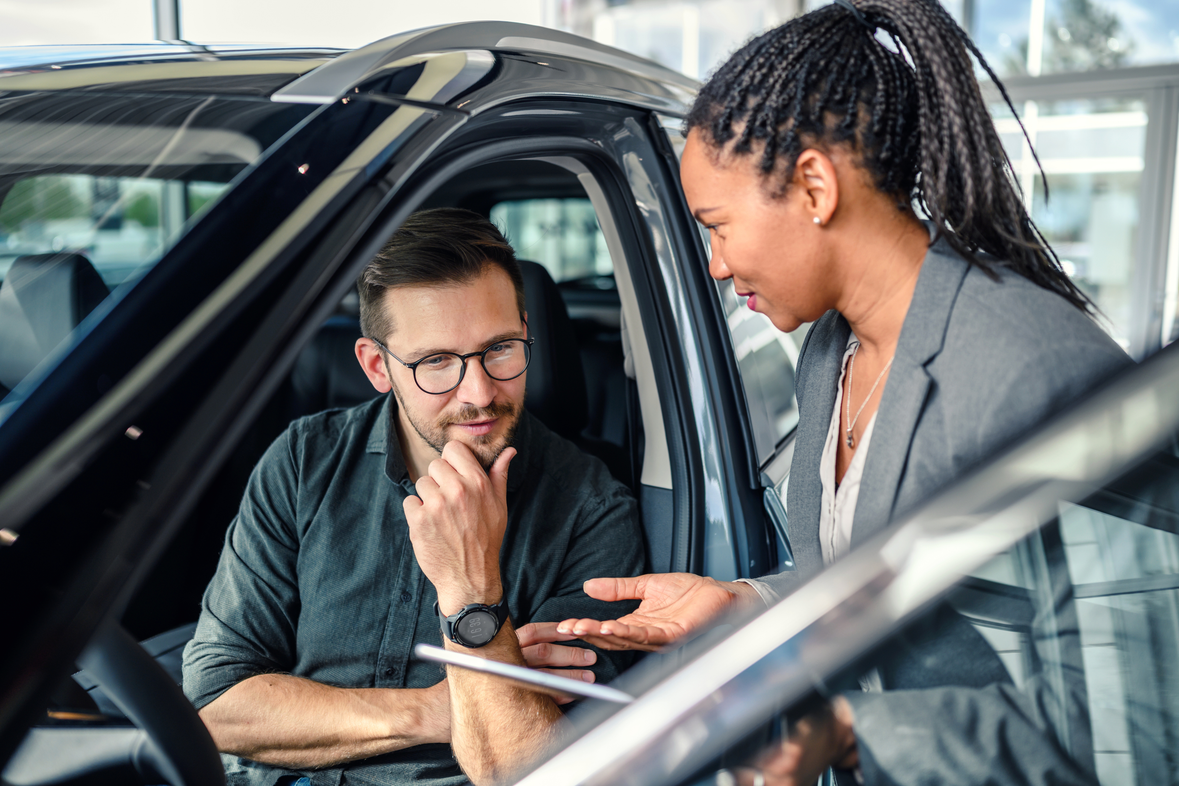 Saleswoman helping the male customer to choose a new car. 