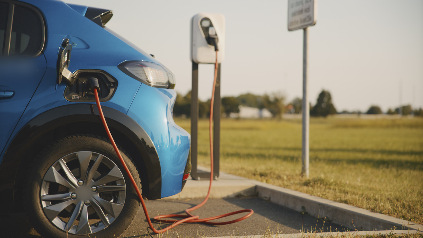  Blue electric car charging at sunny roadside electric vehicle charging station