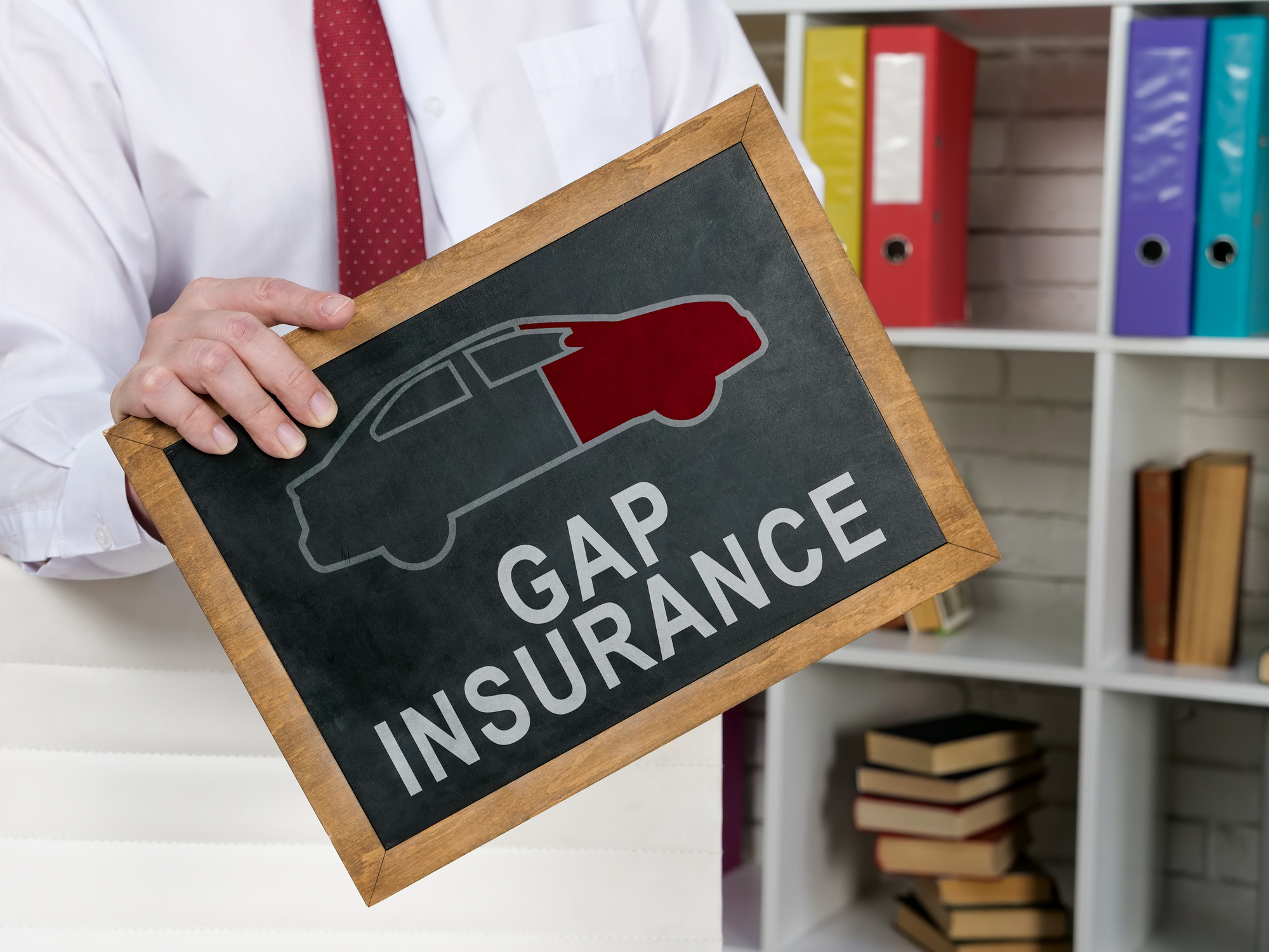 A Man holds blackboard with Gap insurance words on it
