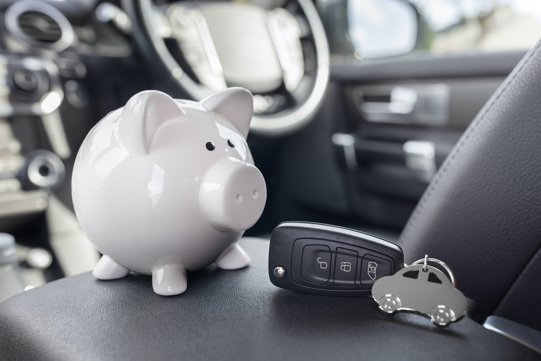 Alt Tag: Piggy bank money box and car key in car interior, vehicle purchase, insurance or driving and motoring cost. 