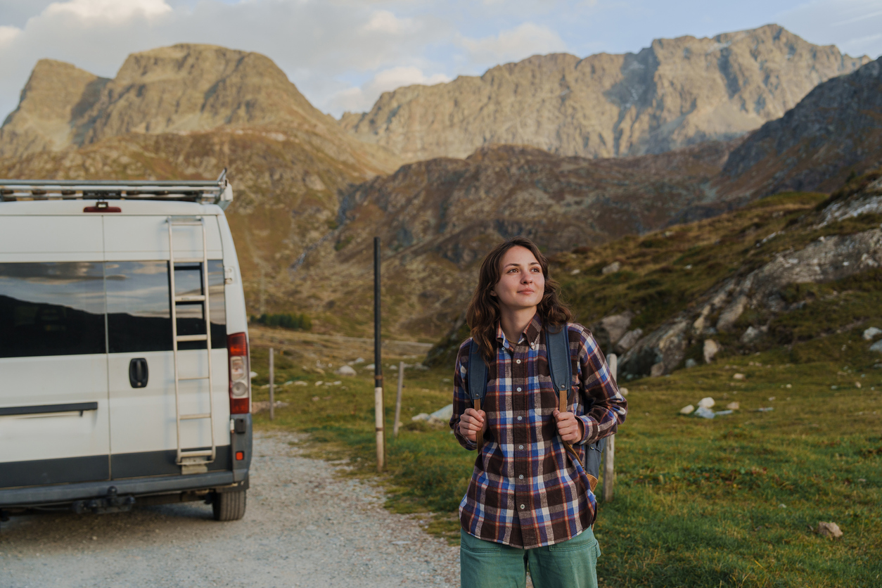 Woman starts hike near the camper van in Alps in autumn. 